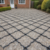 Black permeable ground reinforcement grid installed as a pale gravel driveway at UK residential property