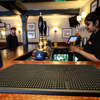 Bartender serving drinks with bar runner mat on counter