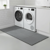 Grey protective floor mat under washing machine utility room