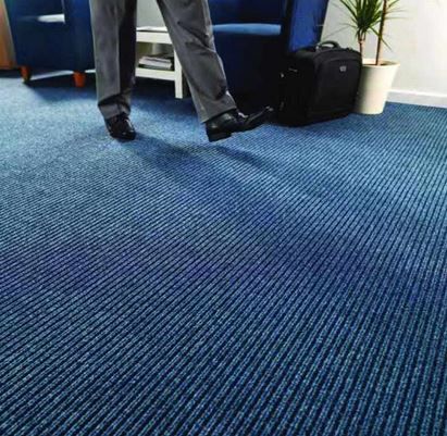 Blue ribbed entrance matting in office reception with businessman