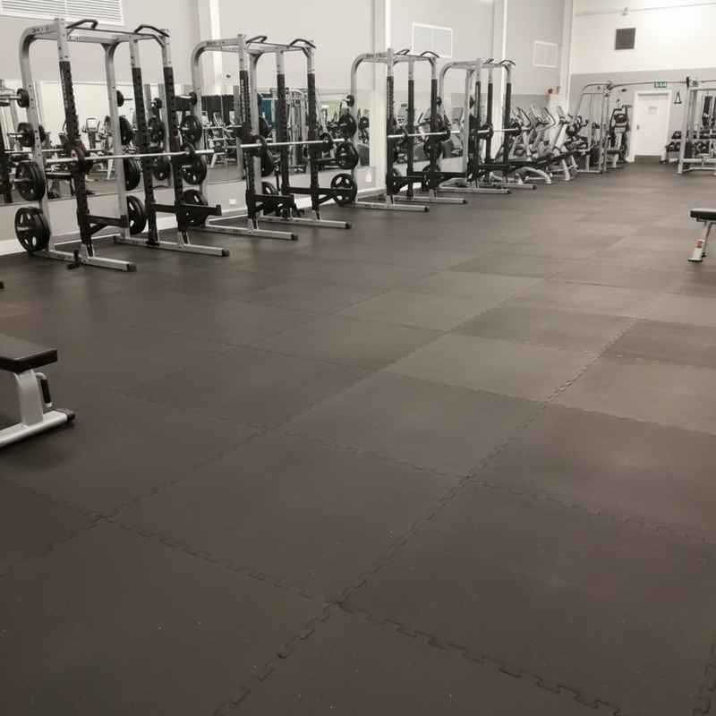 Commercial gym floor covered wall-to-wall with solid black rubber mats