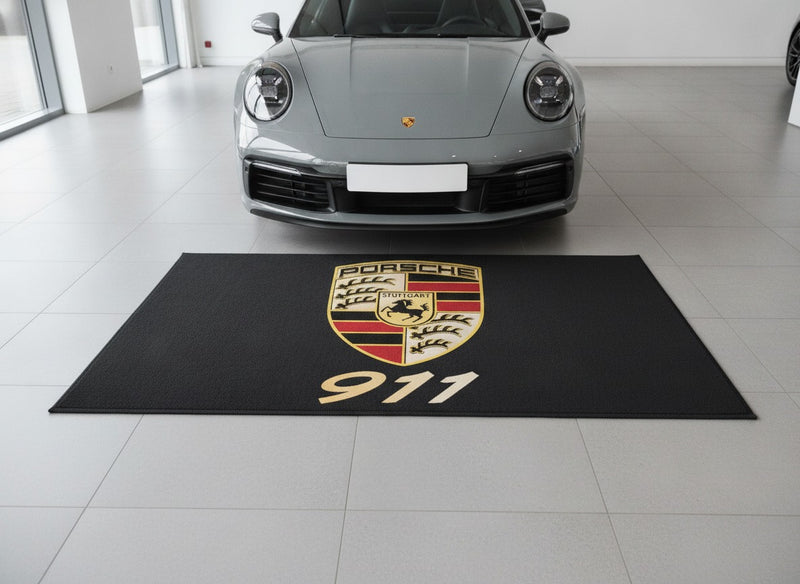 Porsche 911 showroom parking rug in front of a grey 911 Carrera in a bright car showroom