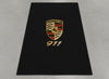 Porsche 911 garage mat flat lay showing the full crest and gold 911 script on black