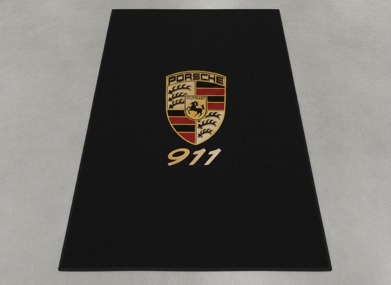 Porsche 911 garage mat flat lay showing the full crest and gold 911 script on black