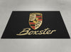 Porsche Boxster garage mat flat lay showing the full crest and gold Boxster script on black