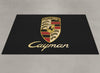 Porsche Cayman garage mat flat lay showing the full crest and gold Cayman script on black