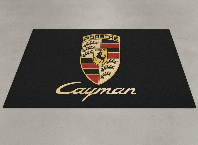Porsche Cayman garage mat flat lay showing the full crest and gold Cayman script on black